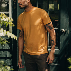 fit model standing in The Cotton Hemp Tee in Mustard, Knits by Taylor Stitch