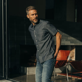 fit model standing in a house wearing The Short Sleeve Hawthorne in Navy Dobby, Wovens by Taylor Stitch