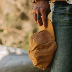 fit model holding by his side The Ball Cap in Tobacco Boss Duck, Accessories by Taylor Stitch