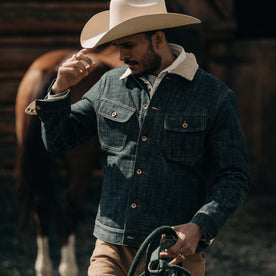 fit model wearing The Lined Long Haul Jacket in Green Cast Denim on a ranch, Outerwear by Taylor Stitch