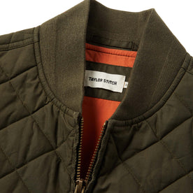 material shot of The Quilted Bomber Vest in Olive Dry Wax showing interior label, Outerwear by Taylor Stitch