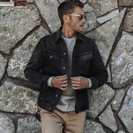 fit model leaning against the wall wearing The Long Haul Jacket in Black 3-Month Wash Selvage, Outerwear by Taylor Stitch