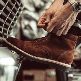 fit model tying the shoelaces on The Moto Boot in Snuff Weatherproof Suede, Footwear by Taylor Stitch