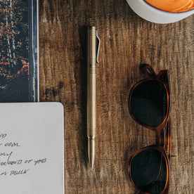 material shot of The Pen in Brass on a wooden table, Accessories by Taylor Stitch