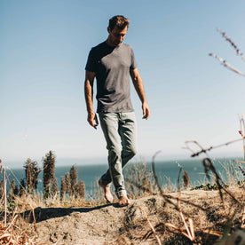 our fit model wearing The Slim Jean in 24-Month Wash Japanese Selvage—walking on the beach, looking down, Denim by Taylor Stitch