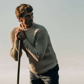 fit model wearing The Adirondack Sweater in Natural, leaning against oar, Knits by Taylor Stitch