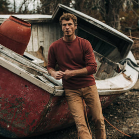 fit model wearing The Crewneck in Brick Red Terry, leaning against boat, Knits by Taylor Stitch