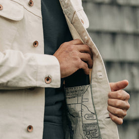 fit model wearing The Long Haul Jacket in Natural Organic Selvage, putting phone in pocket, detail shot, Outerwear by Taylor Stitch