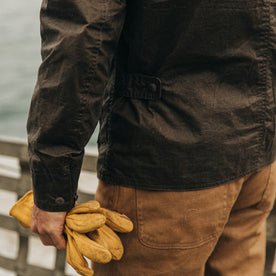 fit model wearing The Longshore Jacket in Dark Oak Waxed Canvas, holding gloves, Outerwear by Taylor Stitch