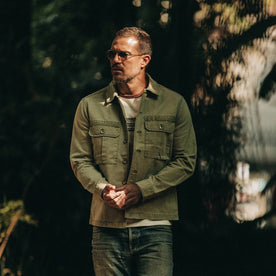 fit model wearing The HBT Jacket in Washed Olive, sunglasses on, looking left, Outerwear by Taylor Stitch