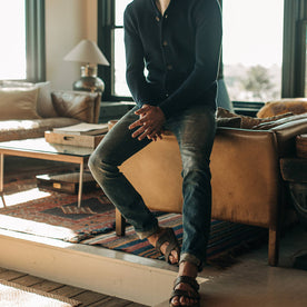 fit model wearing The Slim Jean in Organic Selvage 12-month Wash, sitting against couch, Bottoms by Taylor Stitch