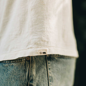 our fit model wearing The Standard Issue Tee in Natural Hemp—logo detail shot, Knits by Taylor Stitch