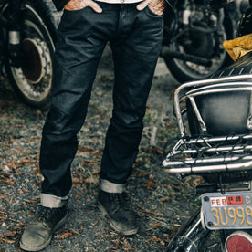 fit model wearing The Democratic Jean in Black Over-dye Selvage, standing near bike, Bottoms by Taylor Stitch