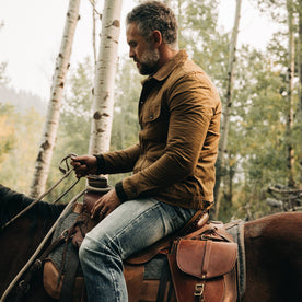 fit model wearing The Lined Long Haul Jacket in Harvest Tan Dry Wax, holding reins, Outerwear by Taylor Stitch