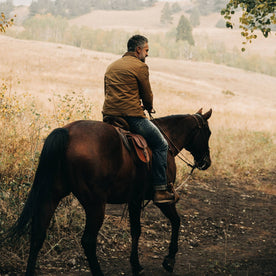 fit model wearing The Lined Long Haul Jacket in Harvest Tan Dry Wax, back on horse, Outerwear by Taylor Stitch