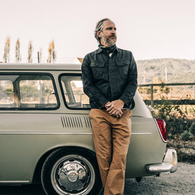 fit model wearing The Long Haul Jacket in Black Over-dye Selvage, leaning against car, Outerwear by Taylor Stitch