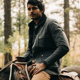 fit model wearing The Rover Jacket in Ripstop Slate Dry Wax, on horse, looking left, Outerwear by Taylor Stitch