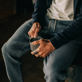 fit model wearing The Après Pant in Charcoal Waffle, sitting, holding coffee, Bottoms by Taylor Stitch