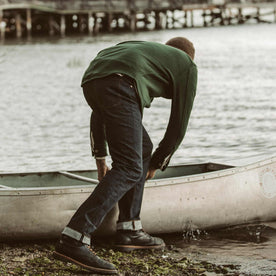 The fit model pushing the canoe out on the water, Denim by Taylor Stitch