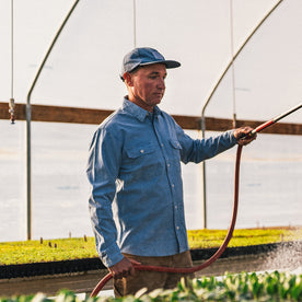 fit model at The Ecolofy Center watering plants in The Chore Shirt in Washed Indigo Boss Duck, Wovens by Taylor Stitch