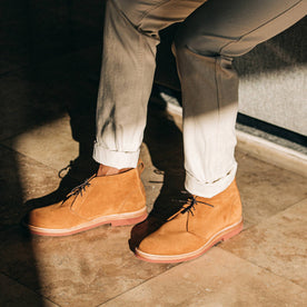 our fit model wearing The Unlined Chukka in Butterscotch Weatherproof Suede—pants cuffed with strong shadows on floor, Footwear by Taylor Stitch