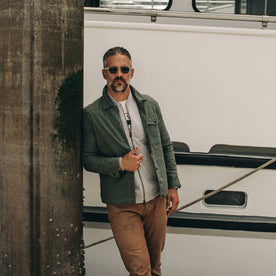 fit model wearing The Lombardi Jacket in Olive Dry Wax, standing on dock, Outerwear by Taylor Stitch