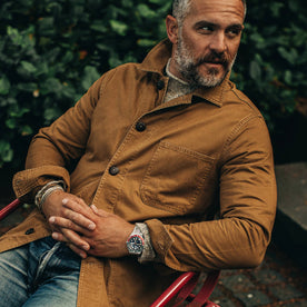 our fit model wearing The Ojai Jacket in Tobacco—sitting in a chair, Outerwear by Taylor Stitch